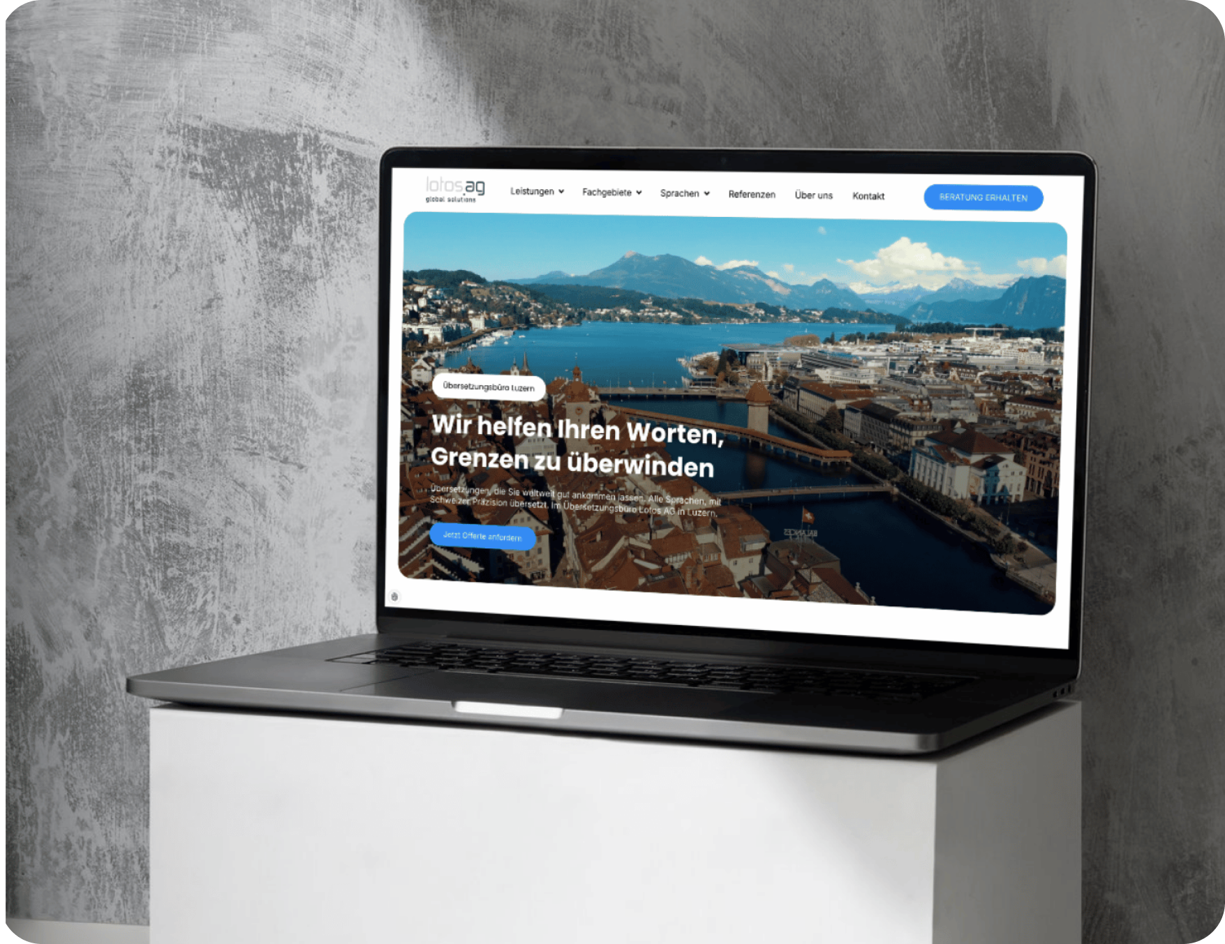 Ein Laptop auf einem weißen Tisch zeigt eine deutschsprachige Website mit einer Stadt- und Seenlandschaft auf dem Bildschirm.