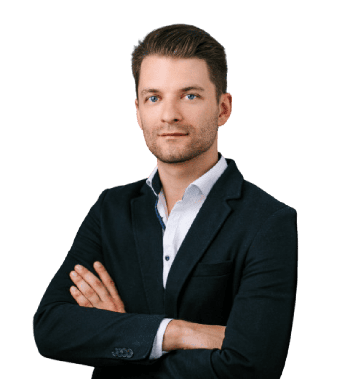 Ein Mann in einem dunklen Jackett und einem weißen Hemd steht mit verschränkten Armen vor einem schlichten Hintergrund und blickt in die Kamera.