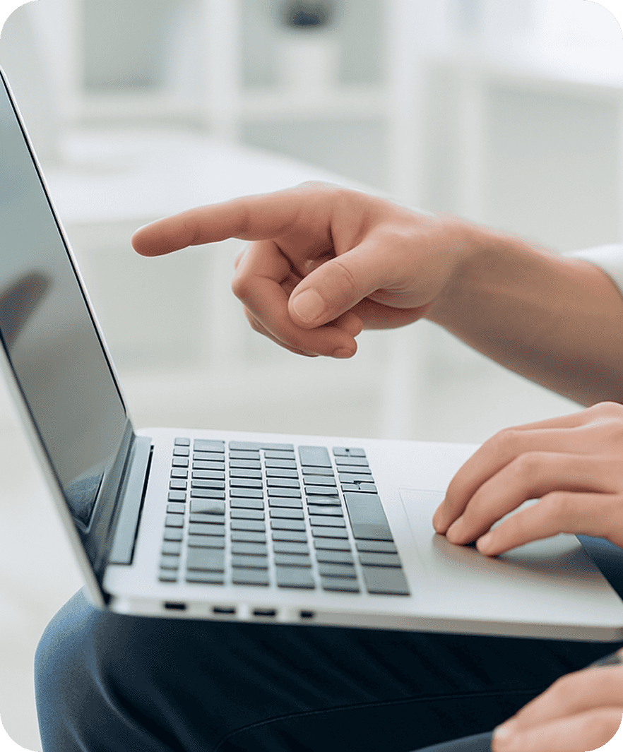 Eine Person zeigt auf den Bildschirm eines aufgeklappten Laptops, während eine andere Hand über der Tastatur schwebt. Sie arbeitet an einem Projekt für die Content Agentur Basel.