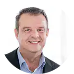 Ein Mann im Geschäftsanzug lächelt in die Kamera vor einem schlichten weißen Hintergrund, bereit, einen aufschlussreichen SEO-Workshop zu leiten.